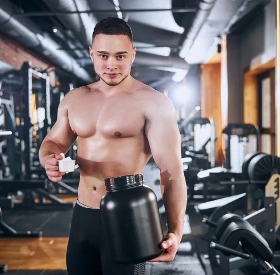 Suplementos Alimenticios: Guía de Uso Completa 2024 3 Hombre en un gimnasio con un bote de proteína en sus manos